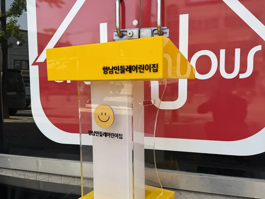 노란 상단에 향남민들레어린이집 이름을 넣고 스마일 로고를 붙인 어린이용 아크릴 단상