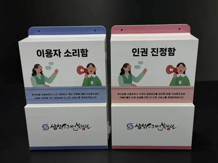 블루 띠 이용자 소리함과 핑크 띠 인권 진정함이 나란히 놓인 삼성소리샘복지관 2종 세트