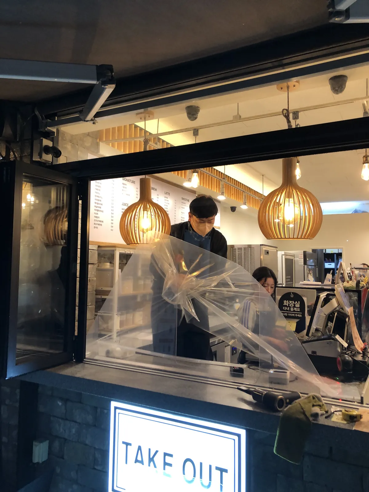 시공 직후 하삼동커피 진영에코시티점 가림막의 보호 비닐을 제거하는 모습